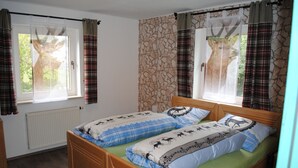 Un dormitorio con dos camas, cortinas de cuadros y una pared con textura de piedra.