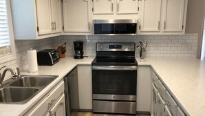 A modern kitchen with white cabinets, stainless steel appliances, and a tiled backsplash.