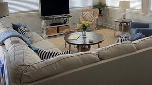 A living room with a sofa, TV, and a ceiling fan.