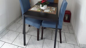 Un coin repas avec une table dressée pour quatre personnes, un vase rempli de fleurs et un caractère chinois rouge peint sur le mur.