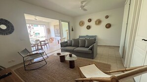 En stue med sofa, sofabord, stol og spisebord. En skydedør fører ud til et udendørs område.