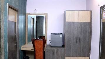 A compact room with a wooden wardrobe, a small refrigerator, and a dining table.