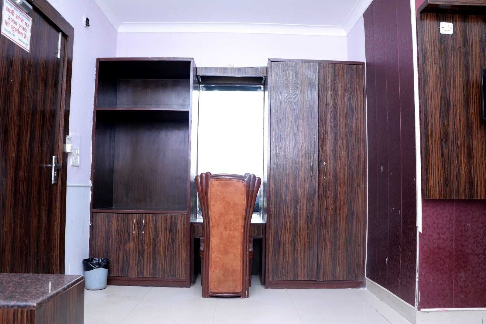 A room with a wooden wardrobe, a small table with chairs, and a window.
