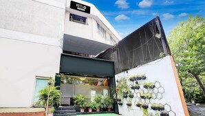 A hotel entrance with a sign reading "HOTEL," potted plants, and a wall-mounted planter with hexagonal shapes.