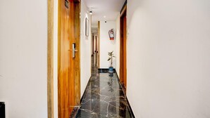 A hallway with wooden doors, a fire extinguisher, and a potted plant.