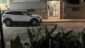 Un SUV blanco estacionado frente a un edificio con un pequeño quiosco iluminado.