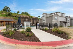 A residential area with a pool, a covered patio, and a gated entrance.