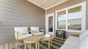 Un espacio exterior acogedor con mesa y sillas de madera, una chimenea y vistas al cielo a través de amplios ventanales.
