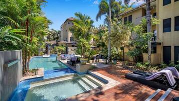 A pool area with lounge chairs and a wooden deck.