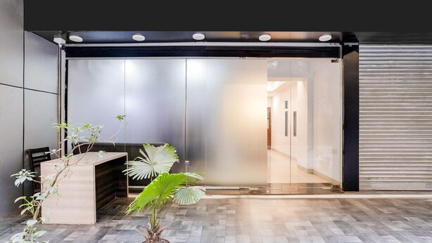 Un espace d’accueil moderne avec une porte en verre, un comptoir d’accueil et une plante en pot.