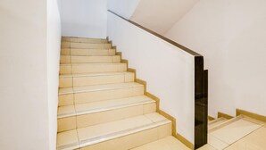 Un escalier avec des marches de couleur beige et une rampe noire, menant à un palier.
