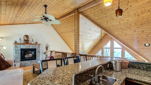 Une cuisine spacieuse dotée d’une cheminée en pierre, de plans de travail en granit et d’un grand îlot central avec un évier.