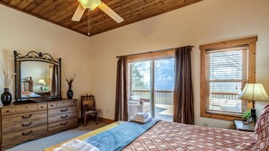Une chambre à coucher comprenant un lit, une commode, une chaise, un grand miroir et un balcon avec vue.