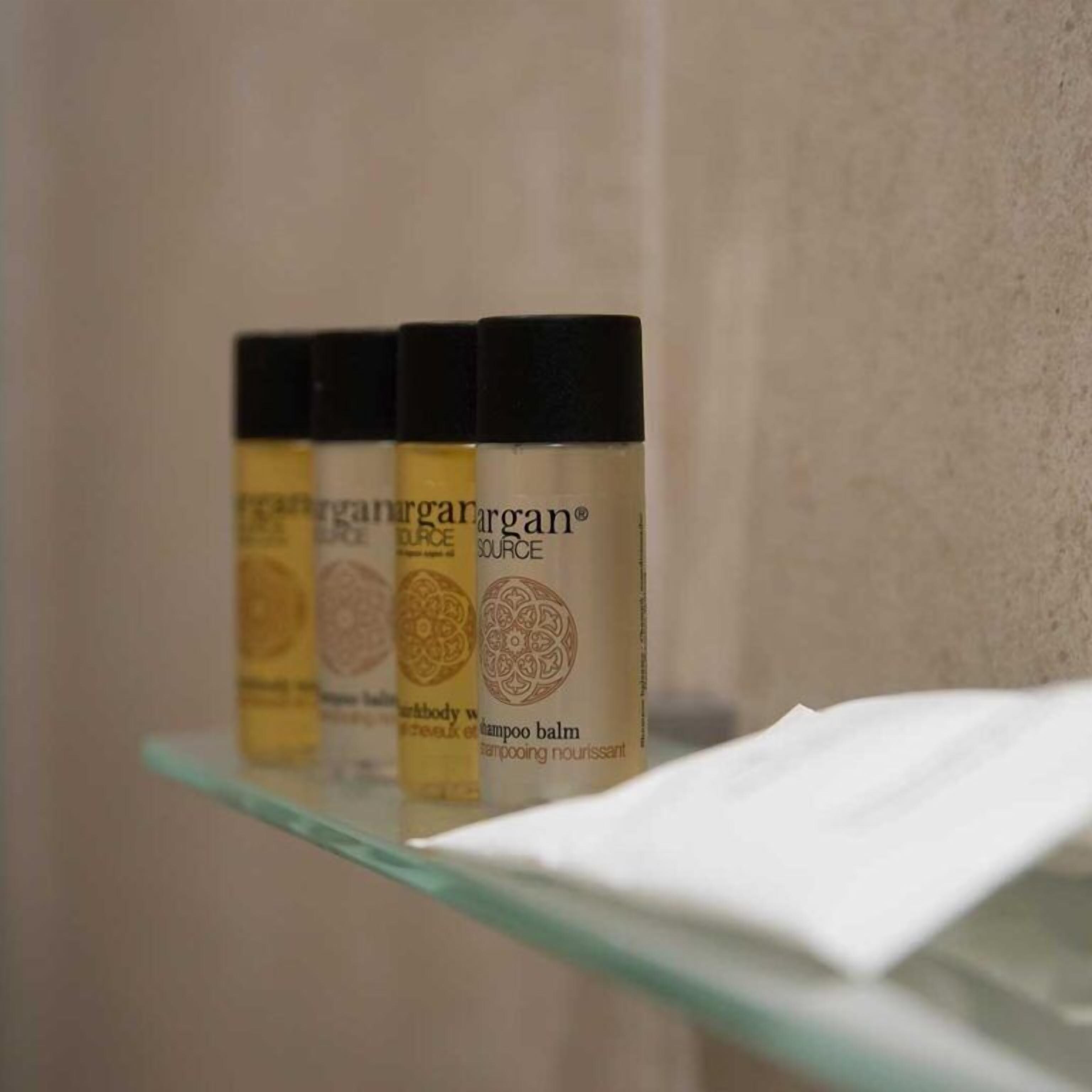 A bathroom shelf with four bottles of argan oil shampoo.