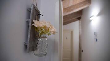Una estantería rústica de pared con un frasco de vidrio transparente que contiene flores pálidas.