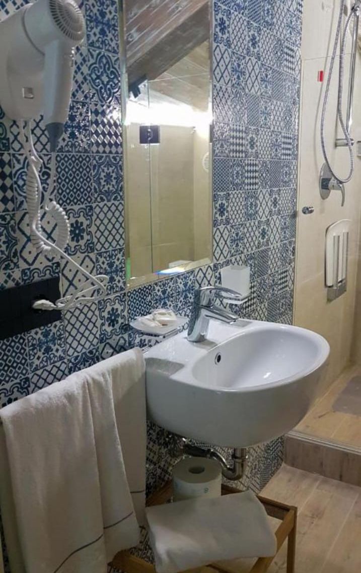 A bathroom with a white sink, a mirror, and a hairdryer on the wall.