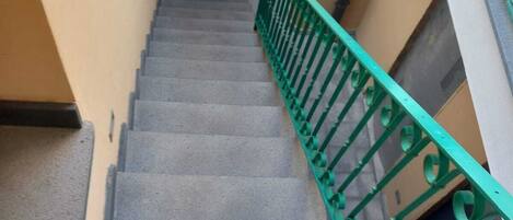 A staircase with a green metal railing leading to a door.