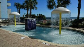 A pool area with water features, palm trees, and a view of the ocean. - Grand Atlantic 1407- Oceanfront - Indoor/Outdoor Pools (Myrtle Beach)