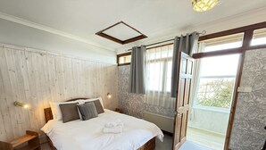 Une chambre avec un lit en bois, une table de chevet, un radiateur et une fenêtre avec des rideaux.