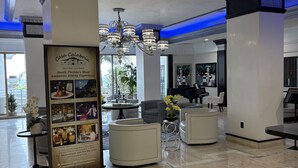 A spacious lobby with a marble floor, a central seating area, and a chandelier.
