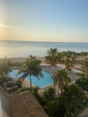 Un resort con piscina, palmeras y vista a la playa.
