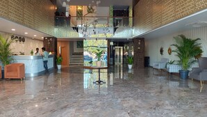 A spacious lobby with a marble floor, a reception desk, and a staircase leading to an upper level. - Tej Hotel & Restaurant  (Tikamgarh)