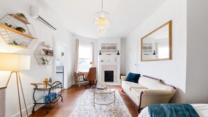 A modern living room with a fireplace, a sofa, a coffee table, and a chandelier. - Historic Suite | Near Mercer University & Downtown (Macon)