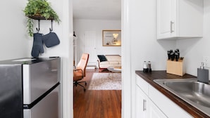 A modern kitchen with a stainless steel refrigerator, a wooden countertop, and a sink. There is a dining area with a sofa and a coffee table. - Historic Suite | Near Mercer University & Downtown (Macon)