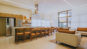 Una cocina moderna con una isla central, comedor con sillas y sala de estar con sofá.