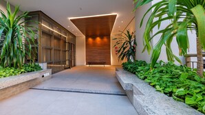 Una entrada moderna con puerta de vidrio, banca y plantas en macetas.