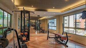 Un gimnasio con equipo de ejercicio variado, ventanas amplias y un patrón de suelo en espiga.