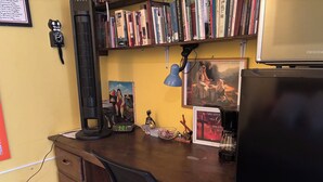 A wooden desk with a computer, books, a clock, a lamp, and a coffee maker. - Charming 2-bedroom apartment with WiFi in Intibuca (Intibuca)