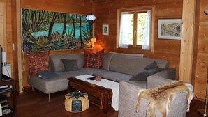 A cozy living room with a sectional sofa, a wooden coffee table, and a painting of a tropical scene.