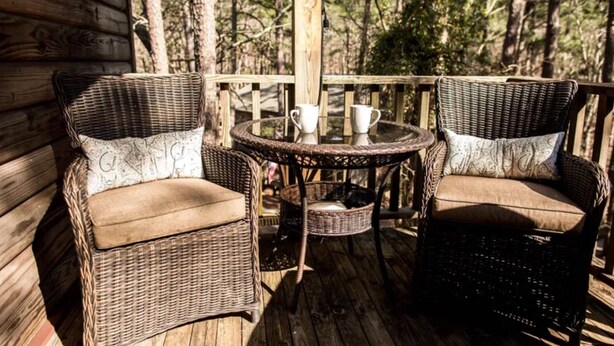Wicker chairs with cushions on a wooden deck, a small round table with cups, and a wicker basket. - Ouachita Weekender 2BR/2BA Condo, Mountain Harbor Resort on Lake Ouachita (Mount Ida)