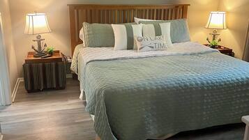 A bedroom with a bed, two nightstands, a ceiling fan, and a wall-mounted painting.