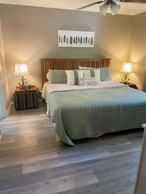 A bedroom with a bed, two bedside tables with lamps, a ceiling fan, and a wall-mounted artwork. - Ouachita Weekender 2BR/2BA Condo, Mountain Harbor Resort on Lake Ouachita (Mount Ida)