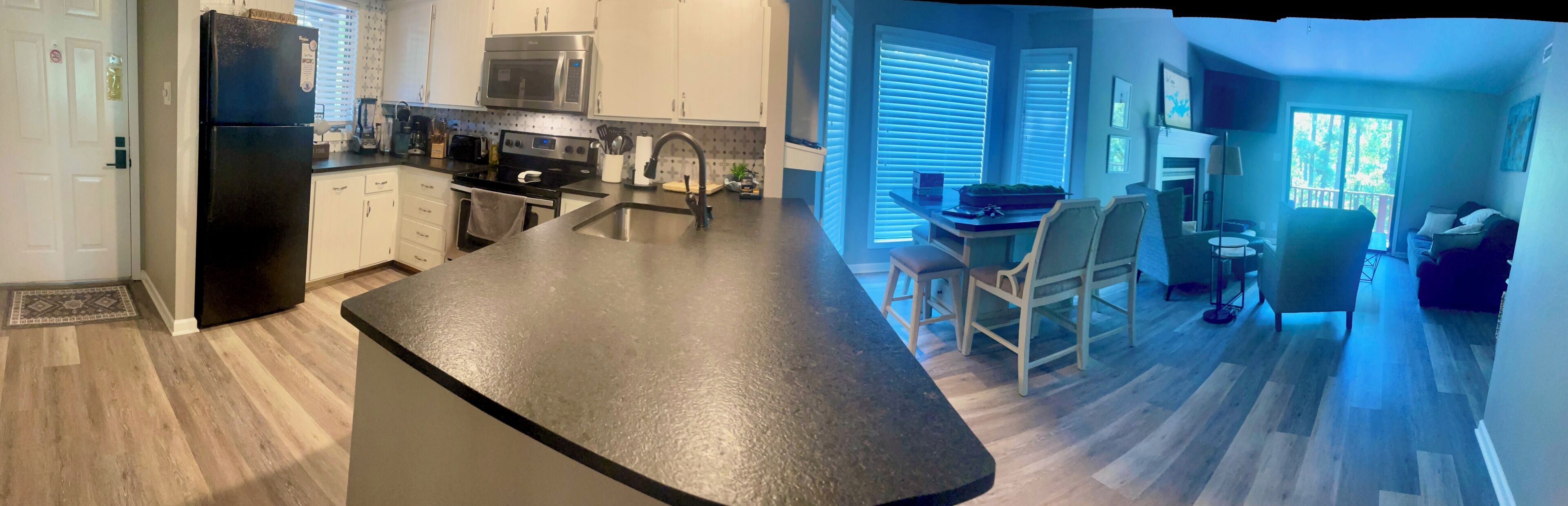 Une cuisine moderne dotée d’un îlot central, d’appareils électroménagers intégrés et d’un coin repas avec des chaises.