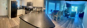 Una cocina moderna con una isla central, electrodomésticos integrados y un comedor con sillas.