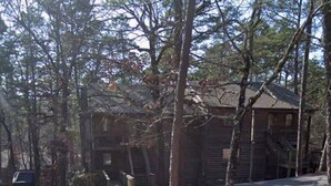 A cabin with a porch, surrounded by trees, and a car parked in the driveway. - Ouachita Weekender 2BR/2BA Condo, Mountain Harbor Resort on Lake Ouachita (Mount Ida)