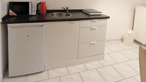A compact kitchen with a microwave, kettle, and a small sink.