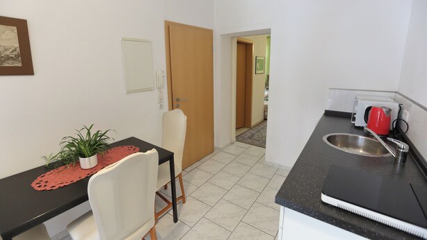 A compact kitchen with a dining area, a sink, and a red kettle.