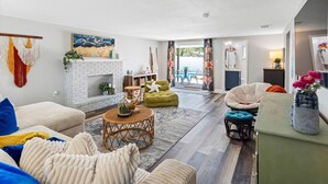 A spacious living room with a fireplace, comfortable seating, and a view of the outdoors. - Charming 3-Bedroom, 2-Bathroom Home with Heated Pool and Spacious Backyard in the Heart of Lakeland (Lakeland)