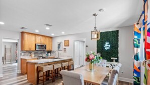 A modern kitchen with wooden cabinets, a central island, and a dining area with a wooden table and chairs. - Charming 3-Bedroom, 2-Bathroom Home with Heated Pool and Spacious Backyard in the Heart of Lakeland (Lakeland)