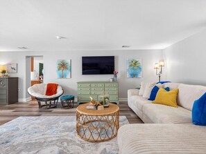 A modern living room with a sofa, armchair, coffee table, and a television.