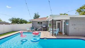 A swimming pool with two inflatable rings, a barbecue area, and a patio with chairs. - Charming 3-Bedroom, 2-Bathroom Home with Heated Pool and Spacious Backyard in the Heart of Lakeland (Lakeland)