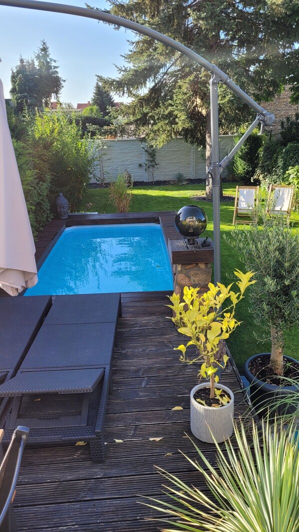 Ein Garten mit Schwimmbad, Liegestühlen und Topfpflanzen.