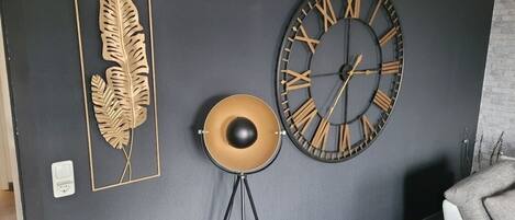Eine Wand mit einer großen Uhr, einem Blatt als Dekoration und einer Stehlampe.