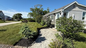 A residential property with a stone pathway leading to a house, surrounded by well-maintained lawns and various shrubs. - Ocean view house (Overton)