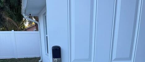 A white door with a keypad lock and a doormat with "WELCOME" written on it.
