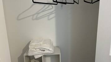 A bathroom with a white towel stack, a toilet paper roll, and a black hanger rack.